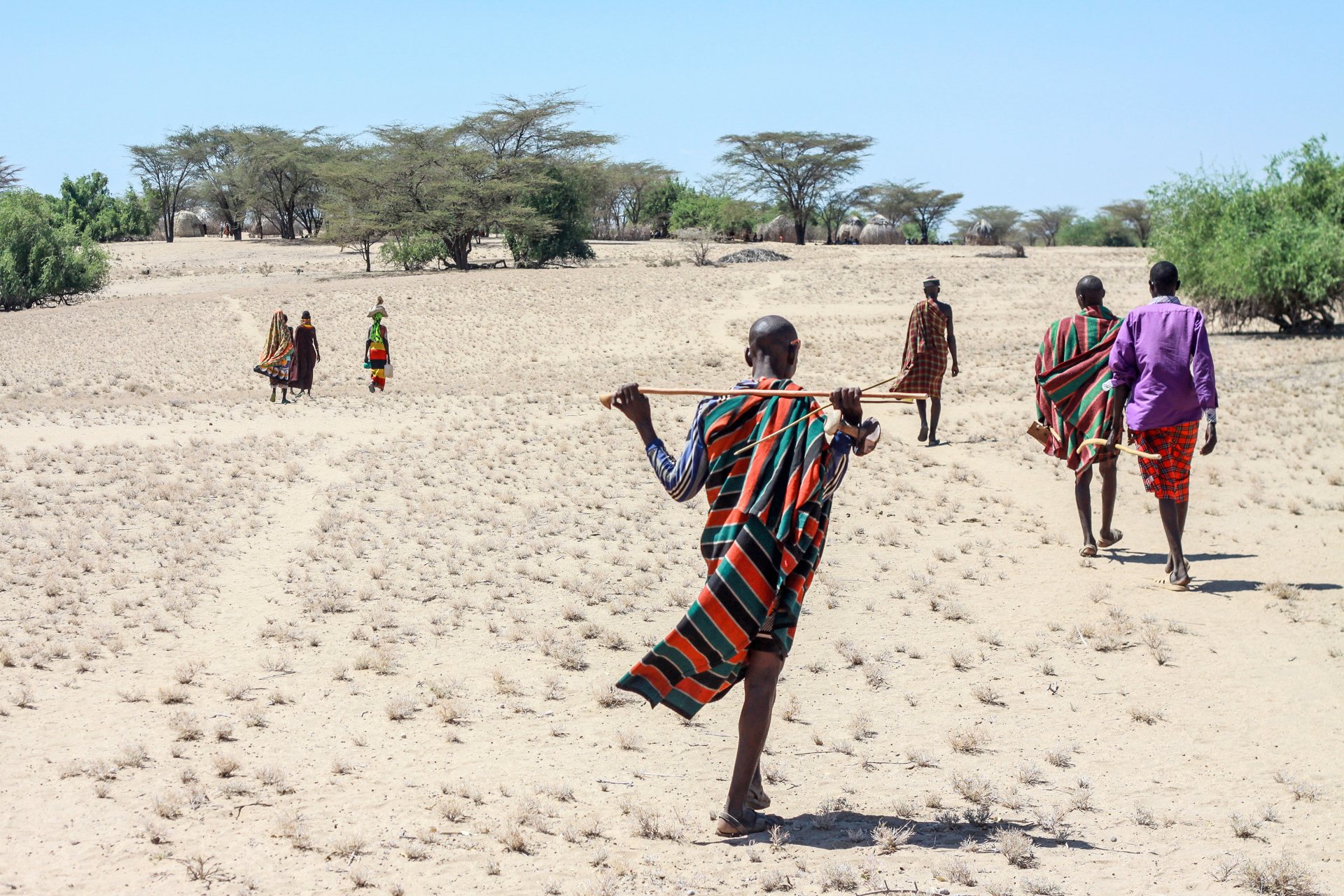 Traditional men and women walking together across the Ateker landscape